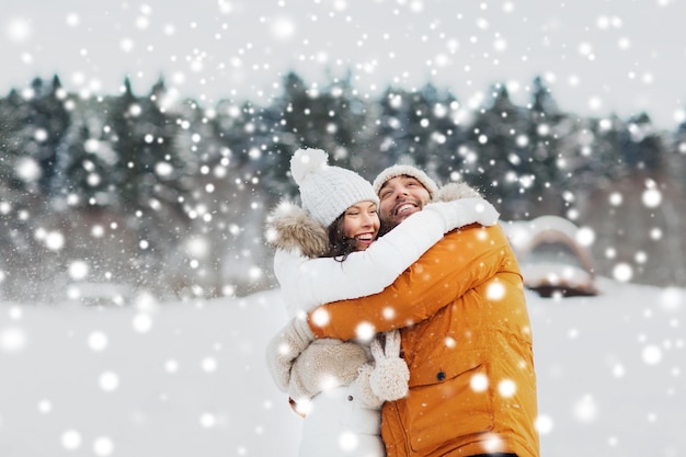 people, season, love and leisure concept - happy couple hugging and laughing outdoors in winter