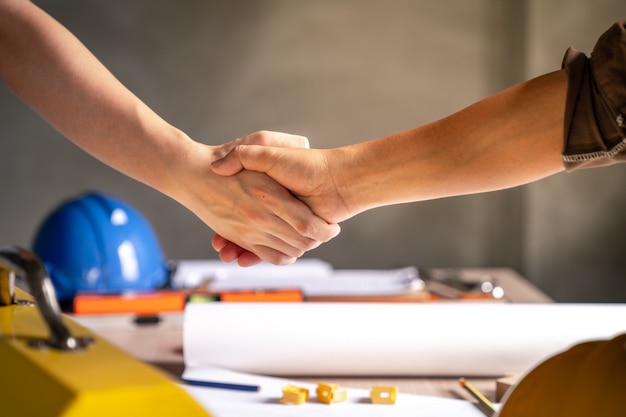 People shake hands above a table with equipment