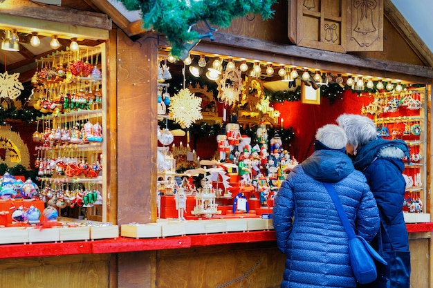 People at the stall on Christmas Market at Kaiser Wilhelm Memorial Church in Winter Berlin, Germany. Advent Fair Decoration and Stalls with Crafts Items on the Bazaar.