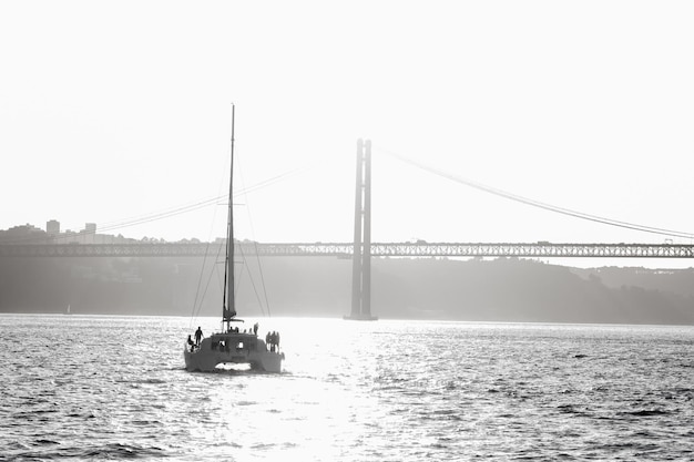 People standing on a sailing yacht sailing along the river towards the bridge