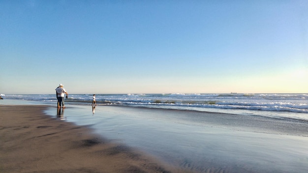 People standing at shore against clear sky