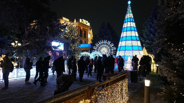 People on the street celebrate new year and christmas fluffy snow is falling beautiful bright decora