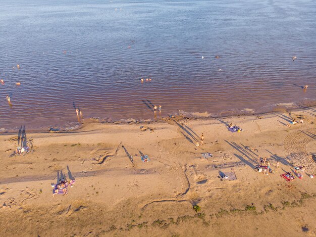 People sunbathe and swim in the lake. Bird's-eye view.