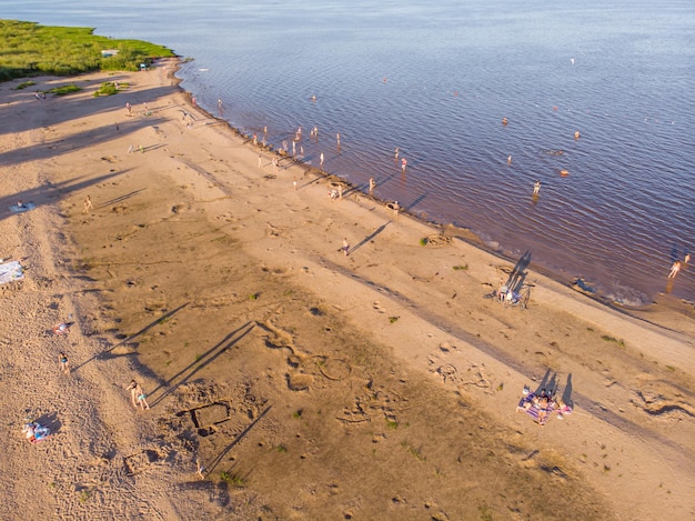 People sunbathe and swim in the lake. Bird's-eye view.