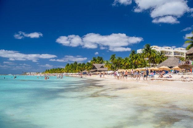 People swimming near white sand beach with umbrellas bungalow bar and cocos palms turquoise caribbean sea Isla Mujeres island Caribbean Sea Cancun Yucatan Mexico