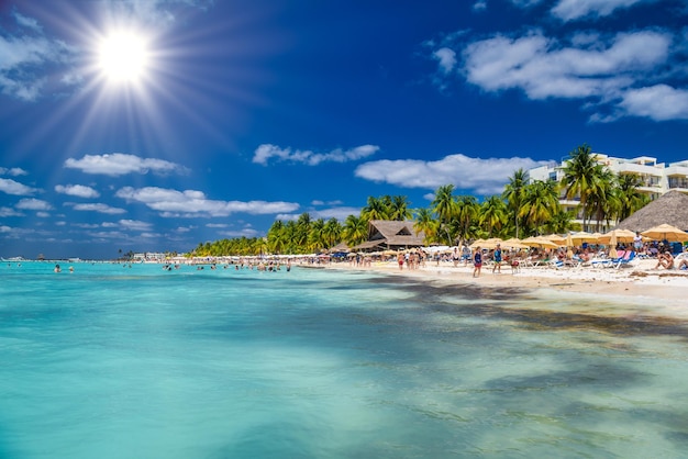 People swimming near white sand beach with umbrellas bungalow bar and cocos palms turquoise caribbean sea Isla Mujeres island Caribbean Sea Cancun Yucatan Mexico