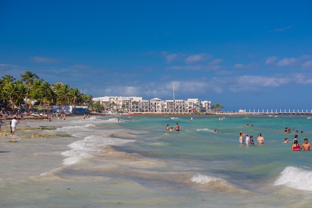 People swimming among splashes and waves on the beach with hotels in Cancun Yukatan Mexico