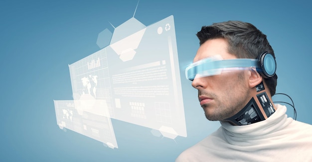 people, technology, future and progress - man with futuristic glasses and microchip implant or sensors over blue background and virtual screens