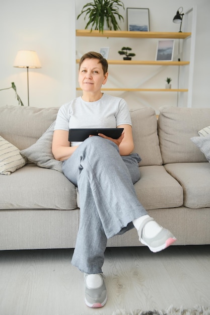 People technology and internet concept happy middle aged woman with tablet pc computer at home