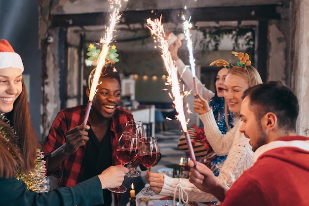 People toasting champagne celebrating with sparklers and looking at each other smiling.