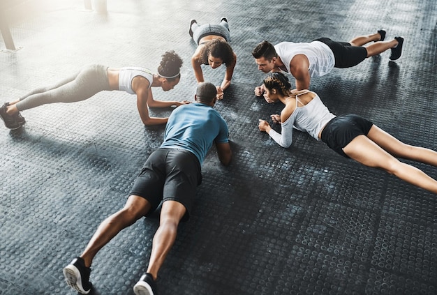 Photo people training and plank in group at gym for workout core exercise or fitness together indoors diverse class friends and warm up for ab muscle session and sport for health on gymnasium floor