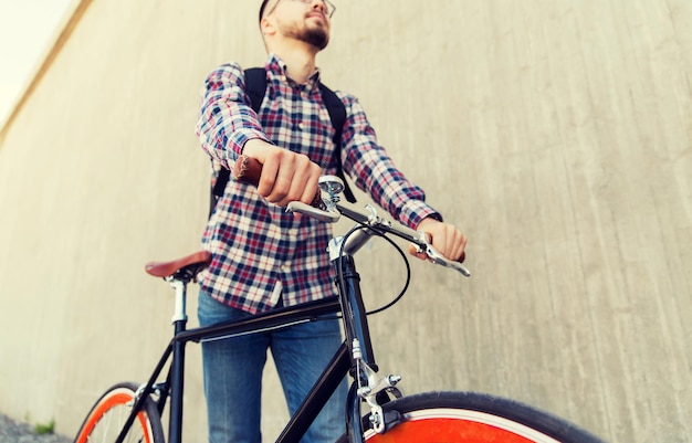 people, travel, tourism, leisure and lifestyle - close up of young hipster man with fixed gear bike and backpack on city street