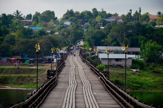 People travel and walk on Saphan Mon wooden bridge in morning time at Sangkhlaburi on December 4 2015 in Kanchanaburi Thailand