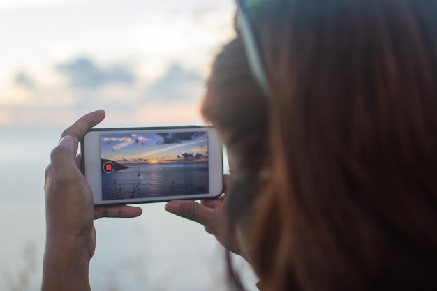 People use and take photo by smartphone on top mountain at evening . subject is blurred.