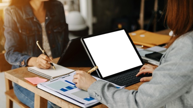 People using and looking at mockup laptop computer on wooden table together on office desk with clipping path tabletxAxA