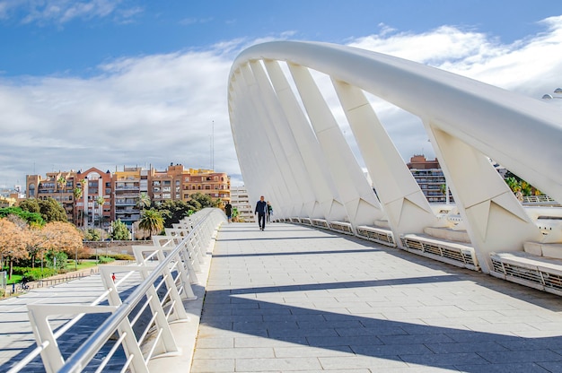 People walk on a sunny day across the Peineta Bridge