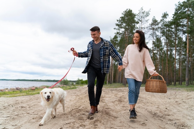 People walking with dog on beach full shot