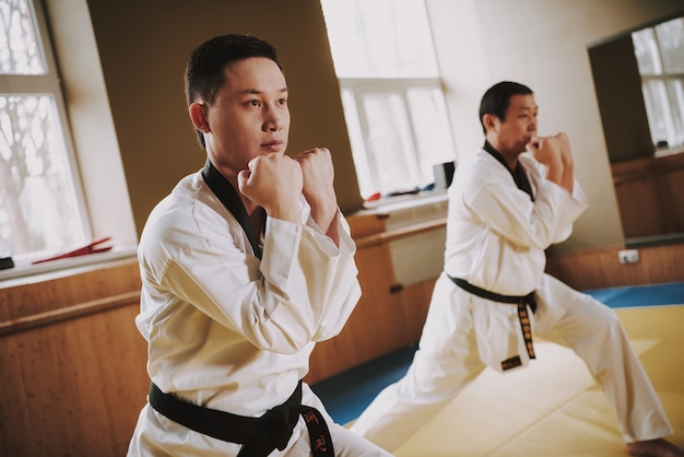 People in white kimono working out racks with jiu jitsu.