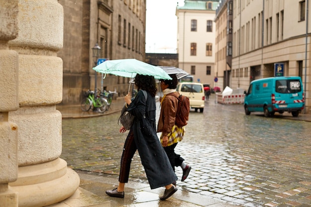 People with umbrellas run through a European city in the rain