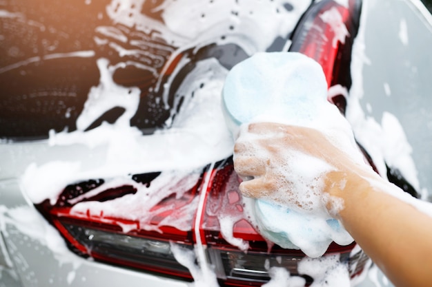 People worker man holding hand blue sponge and bubble foam cleanser window for washing car. Concept car wash clean. Leave space for writing messages.