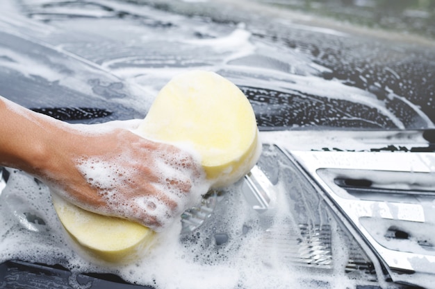 People worker man holding hand yellow sponge and bubble foam cleanser window for washing car. Concept car wash clean. Leave space for writing messages.