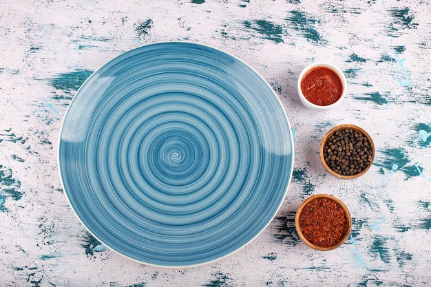 Pepper corns with powder and blue plate placed on stone table. 