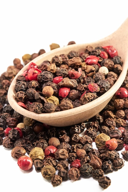 Pepper mixture in wooden spoon on slide pepper mixture closeup on white background condiments spices kitchen Floating Focus Vertical shot