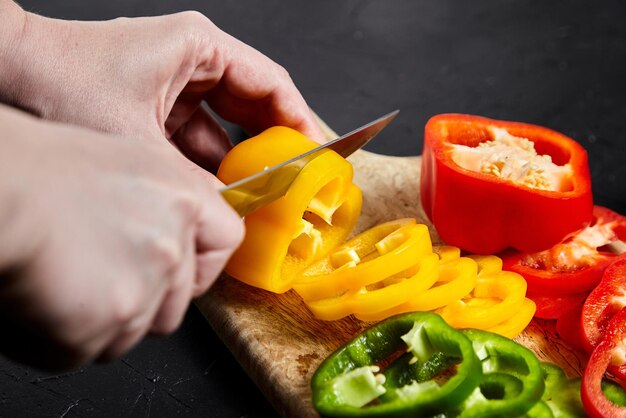 Photo pepper slicing knife and red green yellow bell peppers wooden cutting board sliced sweet pepper