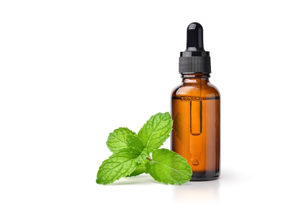 Peppermint essential oil in amber dropper bottle with fresh mint leaf isolated on white background.