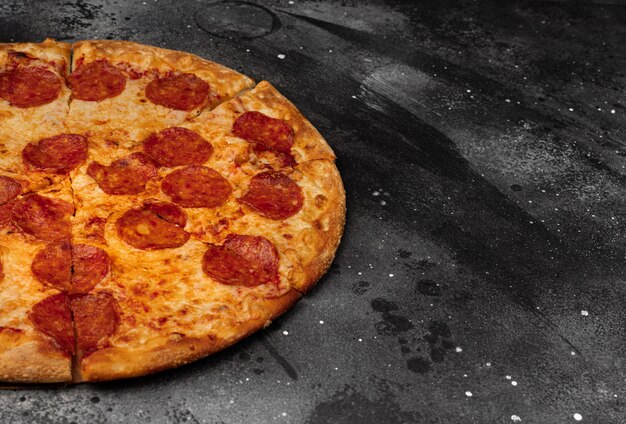 Pepperoni pizza on black concrete background. Top view with copy space.