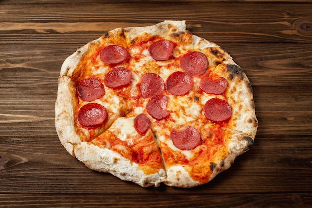 Pepperoni pizza in a box on a white wooden table