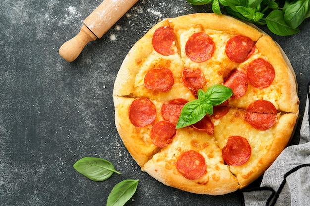 Pepperoni pizza Traditional pepperoni pizza and cooking ingredients tomatoes basil on old concrete texture background table Italian Traditional food Top view Mock up