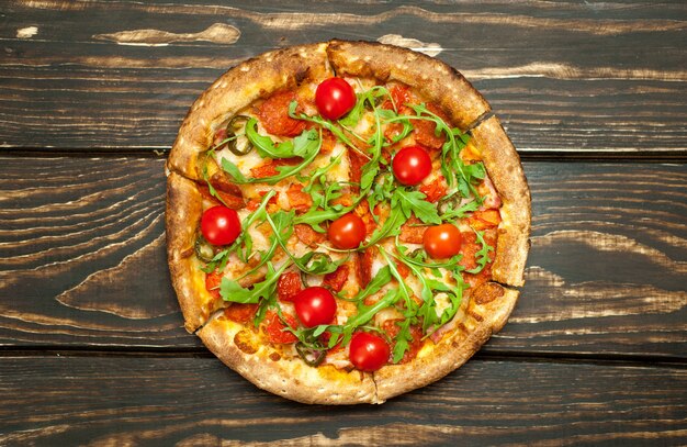 pepperoni pizza with ingredients on wood background