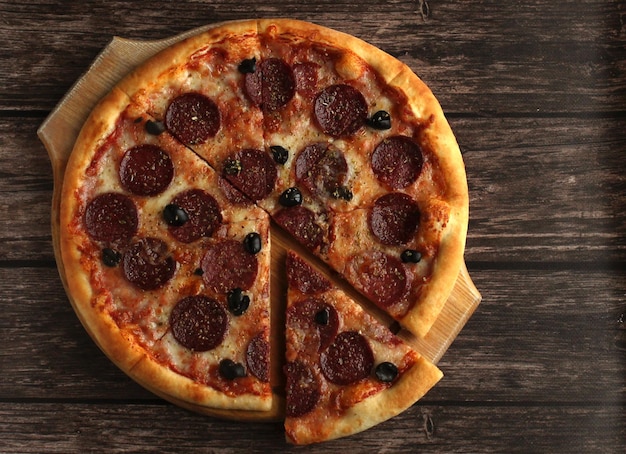 Pepperoni pizza with sausage and olives on a dark wooden background