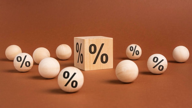 Percent sign on wooden cubes against broun background with wooden balls concept of sale and discount