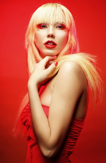 Perfect blond model in red dress over red background