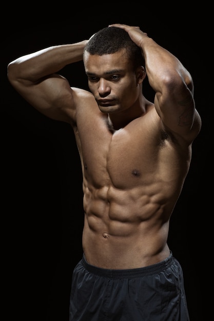 Perfect body. Vertical shot of an African man with toned body posing shirtless in studio