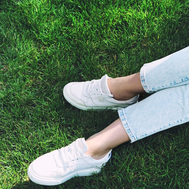 Perfect legs with white sneakers against green grass lane top view