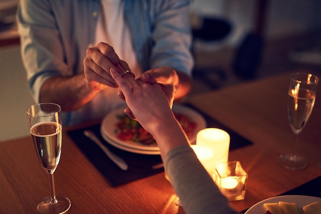 The perfect occasion Cropped shot of an unrecognizable man proposing to his wife over a candle lit dinner at night