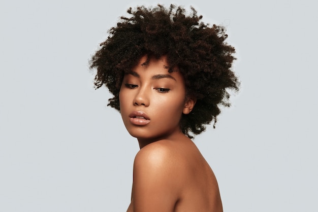 Perfect skin. Attractive young African woman looking away while standing against grey background