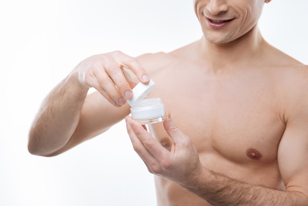 Perfect skin moisturizer. Close up of a moisturizing cream bottle being opened by a happy delighted nice man