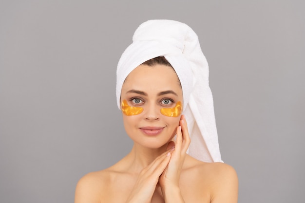 The perfect skincare. applying golden anti-fatigue mask. girl reduce eye bags. facial collagen cosmetic. moisturizing skin. cosmetology. young woman in terry towel use patch. beauty day in spa.