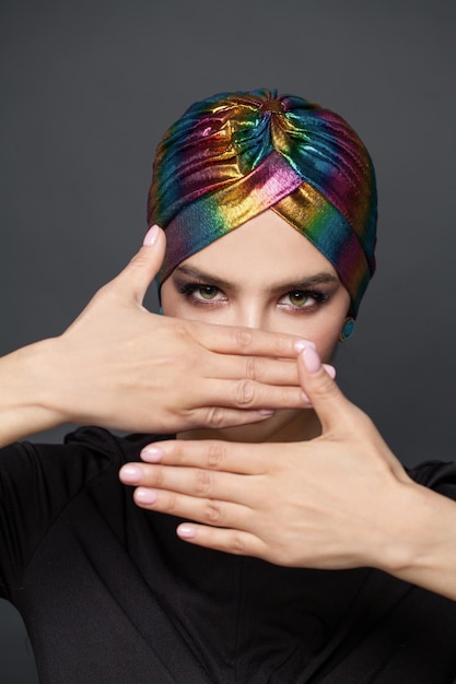 Photo perfect stylish woman in traditional turban hat on her head hiding her face her hands