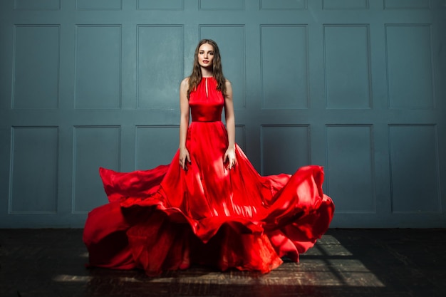 Perfect Woman in Red Dress. Beautiful Fashion Model on Blue Background