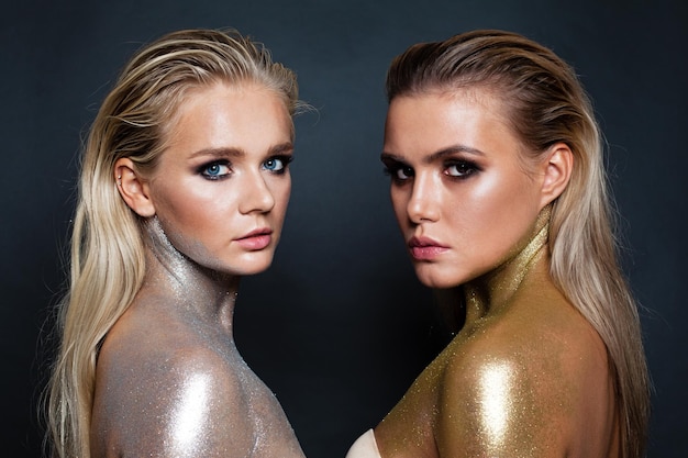 Perfect women models with gold and silver glitter makeup on dark background