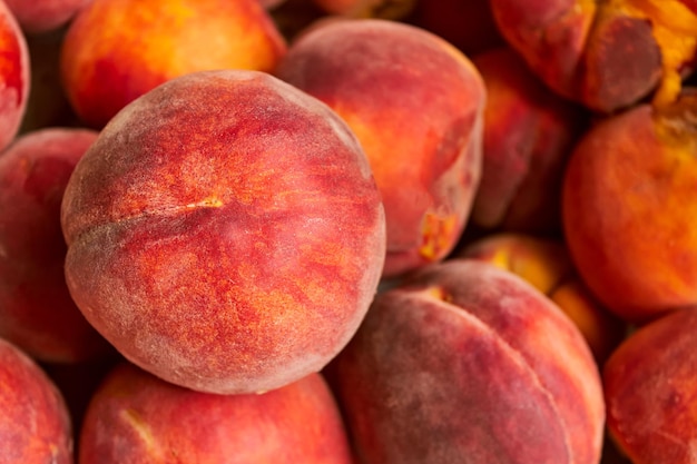 A perfectly ripe orange peach lying on a pile of other fruits Top view Summer fruit harvest closeup