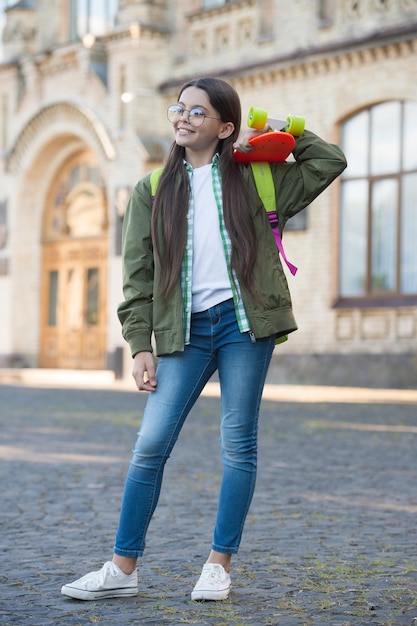 Performing tricks with skate board Happy kid hold penny board Little skater smile outdoors Transportation Recreational activity Action sport Travel and adventure Keeping the good times rolling