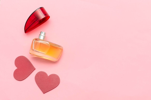 Perfume bottle as gift and red hearts on a pink background with copy space Valentines Day