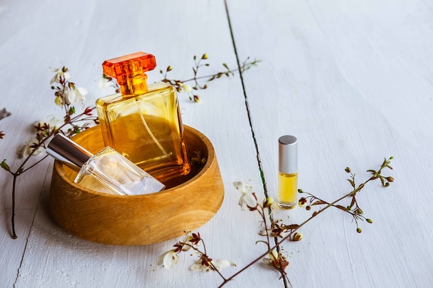 Perfume bottle with flowers on a white wooden background