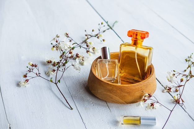 Perfume bottle with flowers on a white wooden background